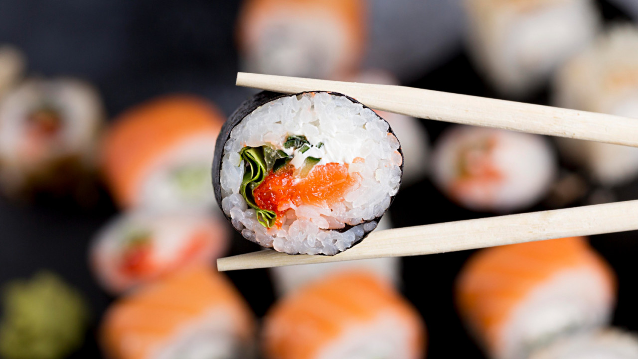 close up chopsticks with sushi roll