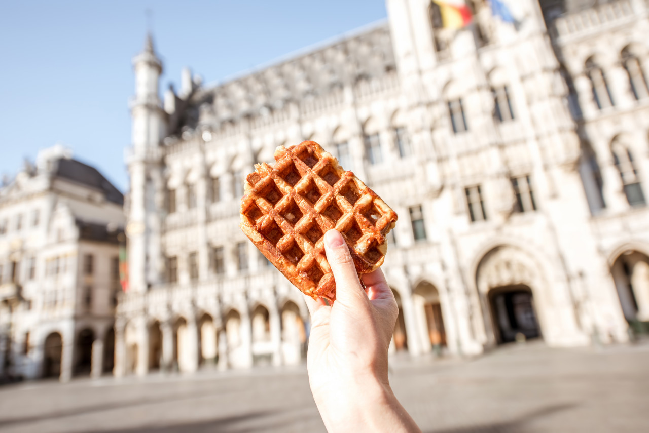 holding traditional belgian waffle central square background with city hall brussels belgian food concept
