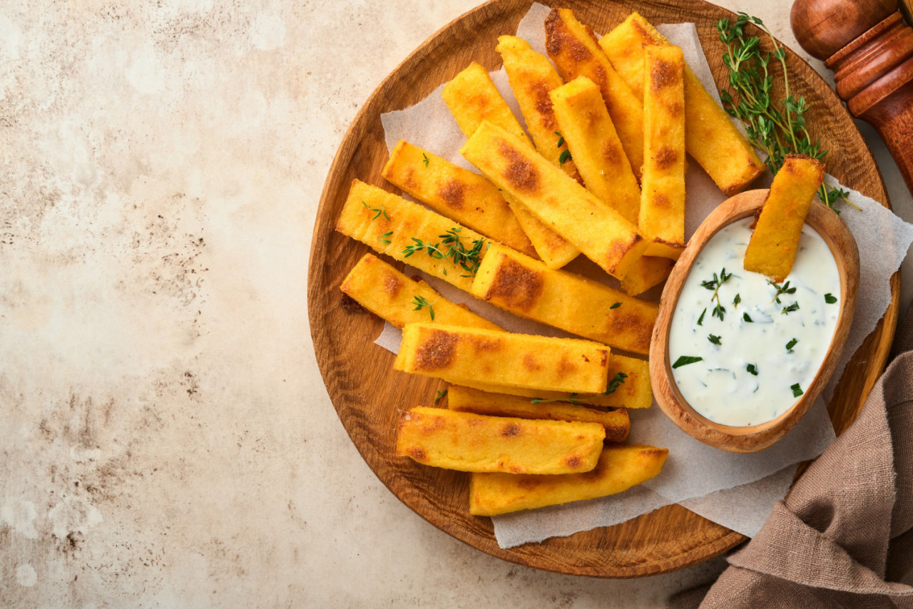 homemade polenta chips fries with sea salt parmesan thyme rosemary with yogurt sauce typical italian fried polenta fried corn sticks old light concrete background top view