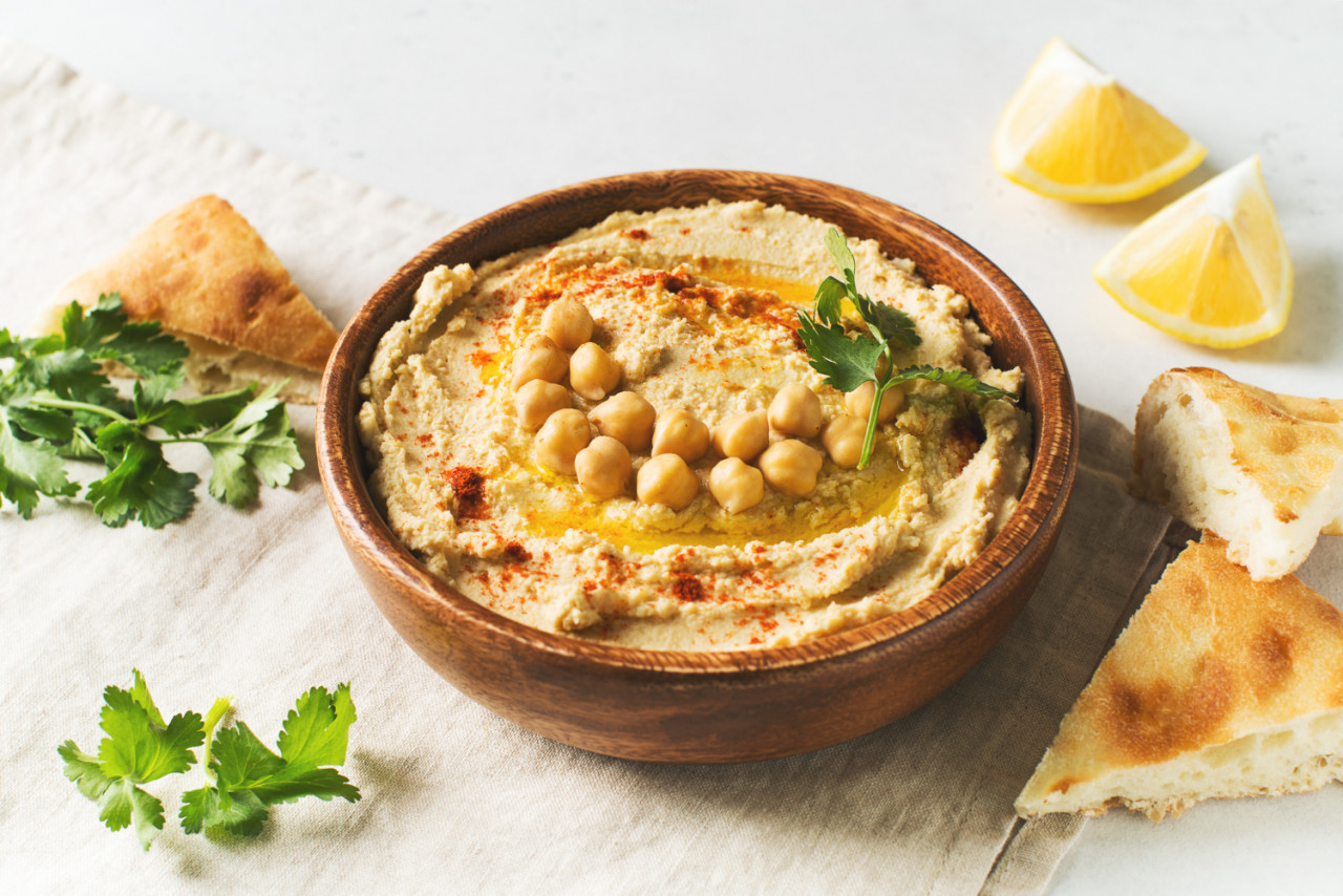 hummus dip with chickpea pita parsley wooden plate white background