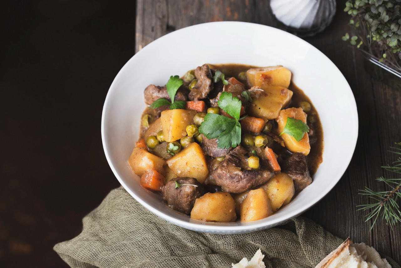 portion traditional irish beef guinness beer stew with carrots potatoes green peas