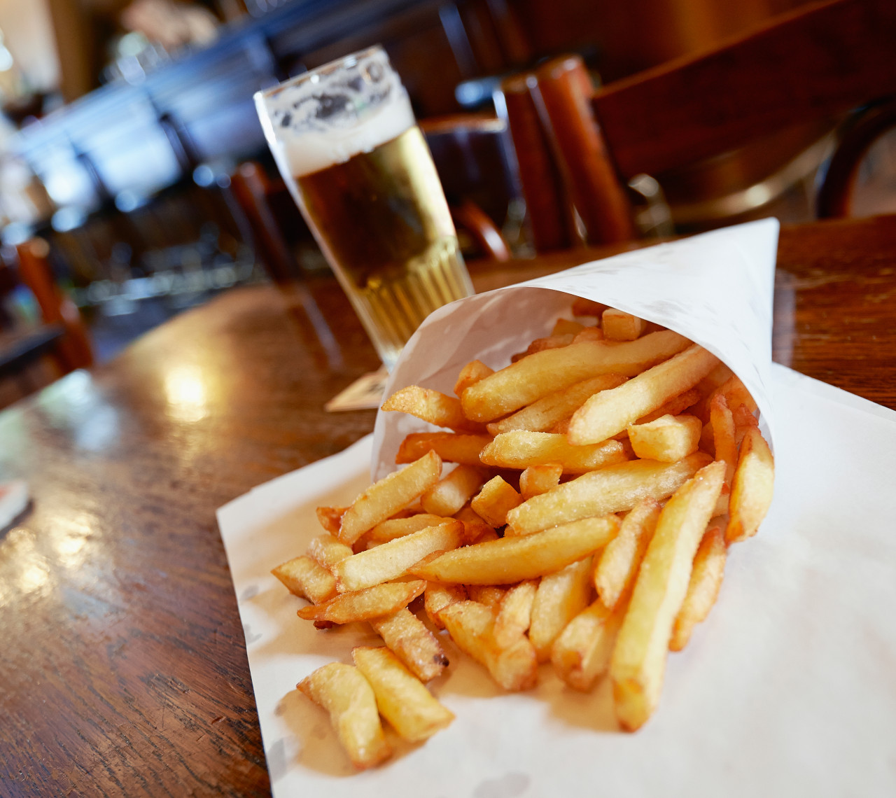 potatoes fries little white paper bag wood table brussels pub