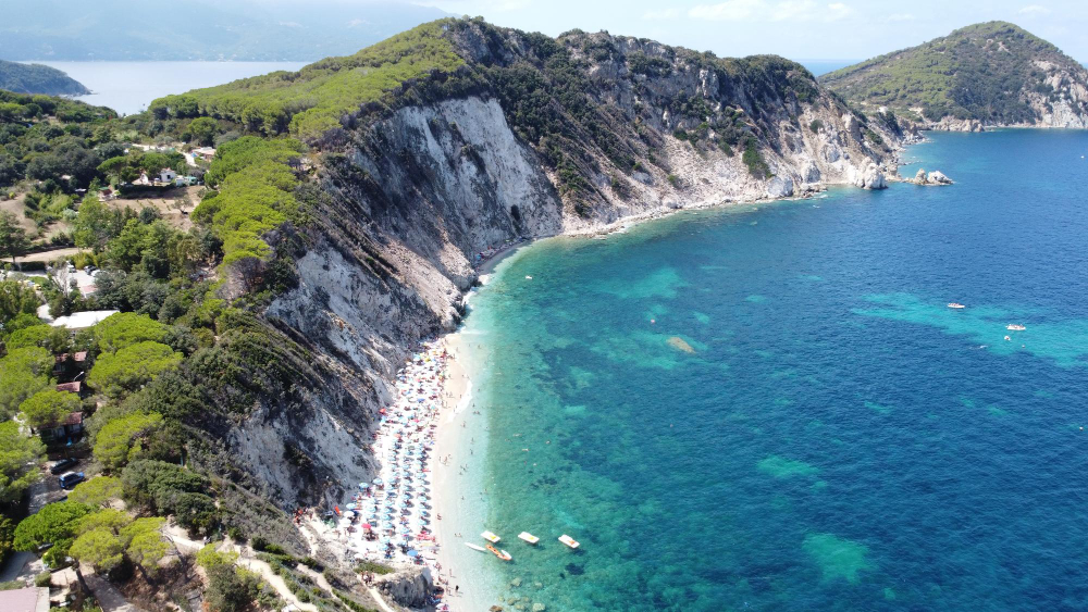 ripresa aerea del turista con ombrelloni nel parco nazionale dell arcipelago toscano italia