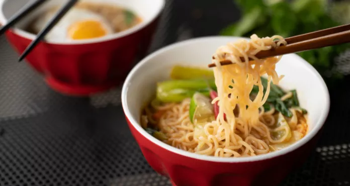 Close Shot Chopsticks With Noodles Near Soup With Blurred Background