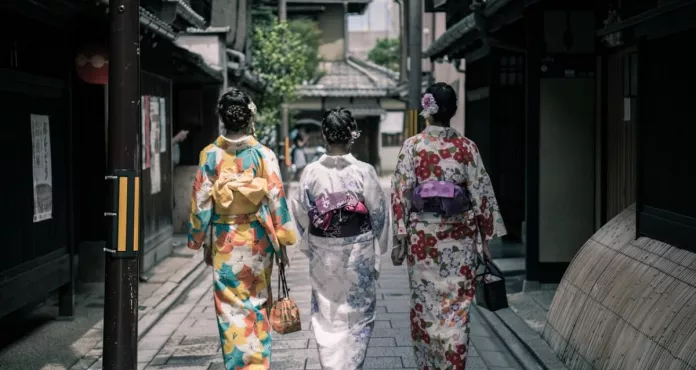 Three Geisha Walking Between Buildings