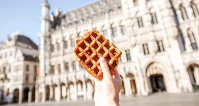 Holding Traditional Belgian Waffle Central Square Background With City Hall Brussels Belgian Food Concept