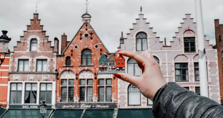 Person Holding Miniature House Toy Comparing On Real Building
