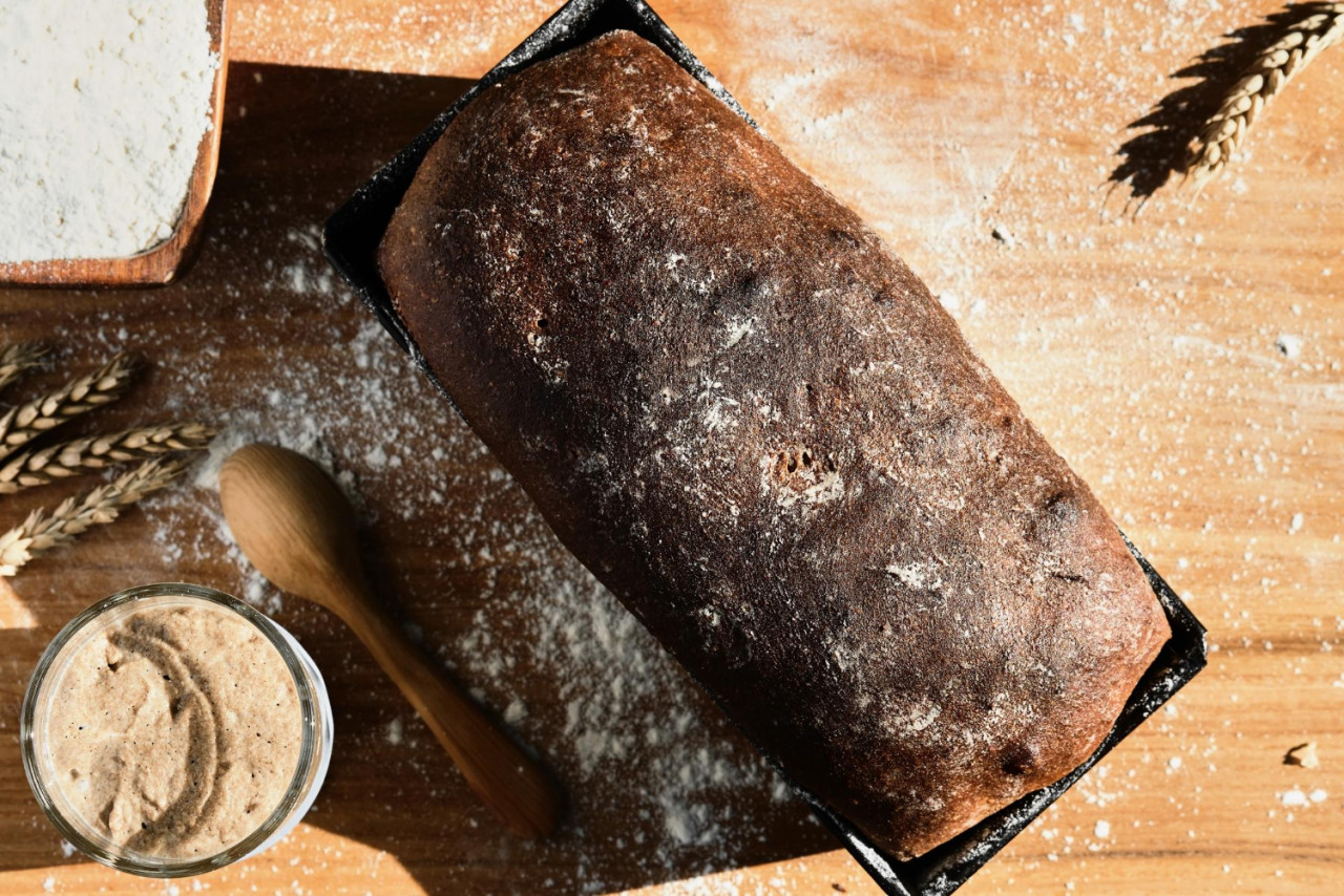 active rye wheat sourdough starter glass jar ingredient flour freshly baked whole grain bread laid out table