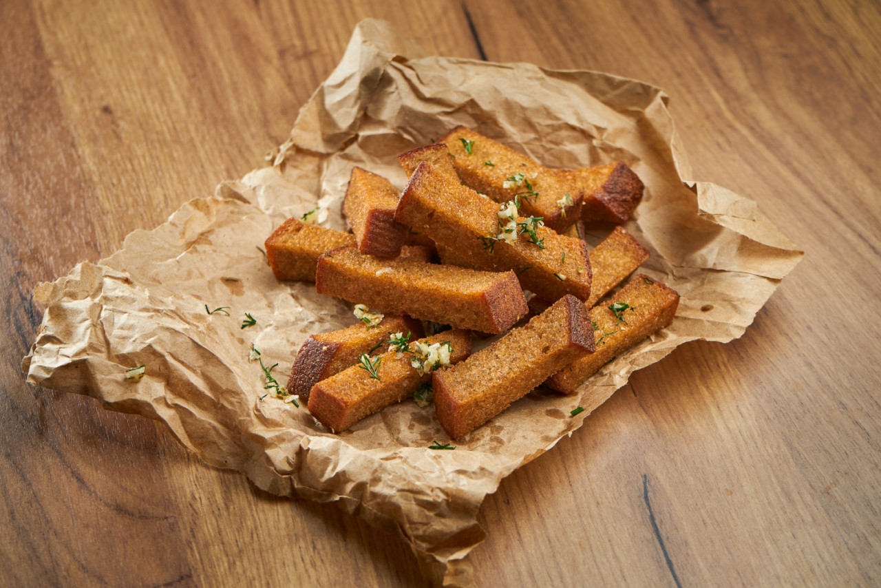 appetizing snack with beer rye croutons with garlic herbs parchment wooden surface