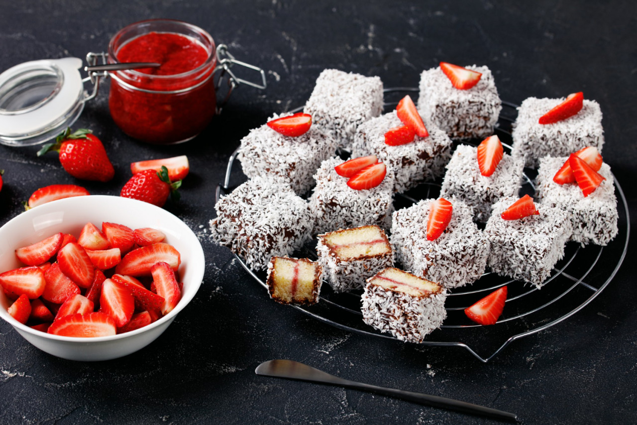 australia s famed dessert lamingtons with strawberry jam filling coated with chocolate and shredded coconut served on a round wire rack