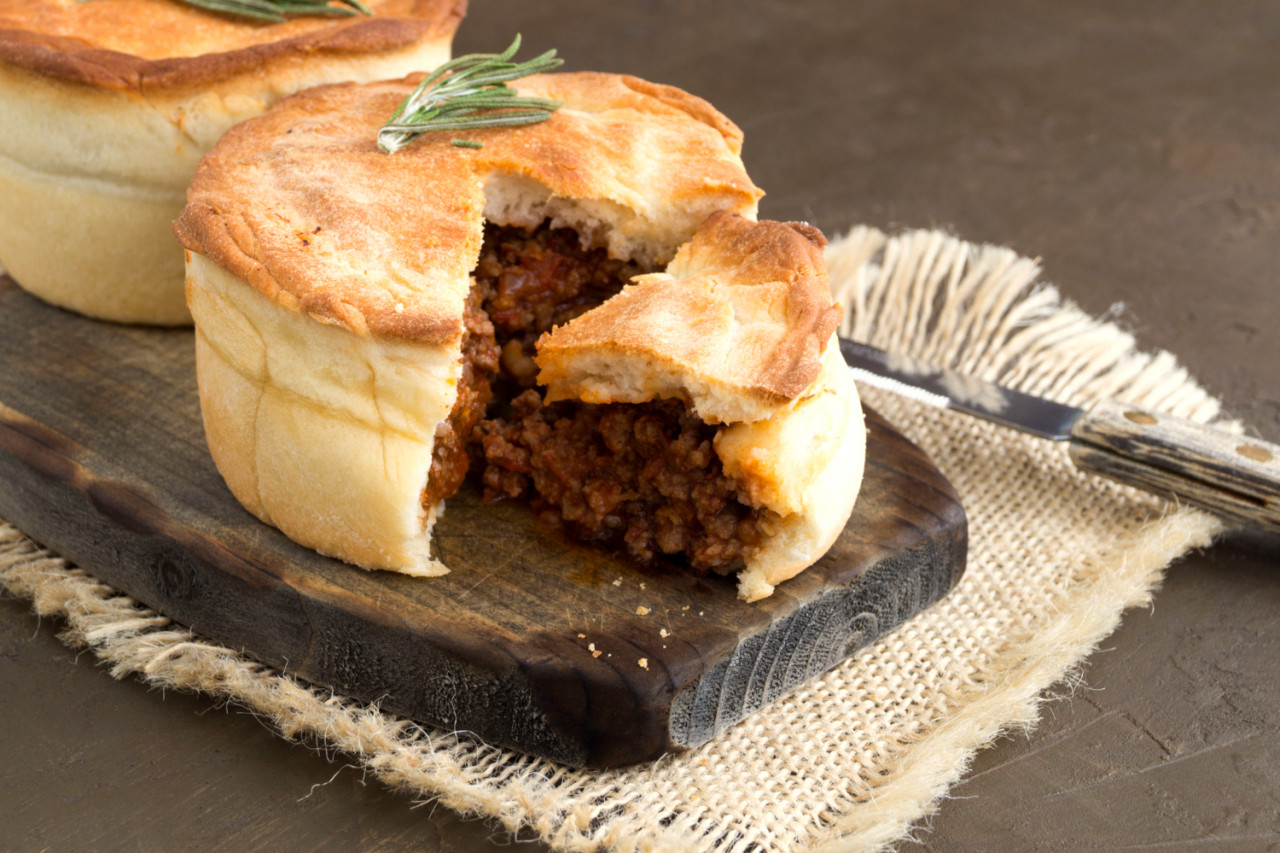 australian meat pie on wooden table close up with copy space rustic style