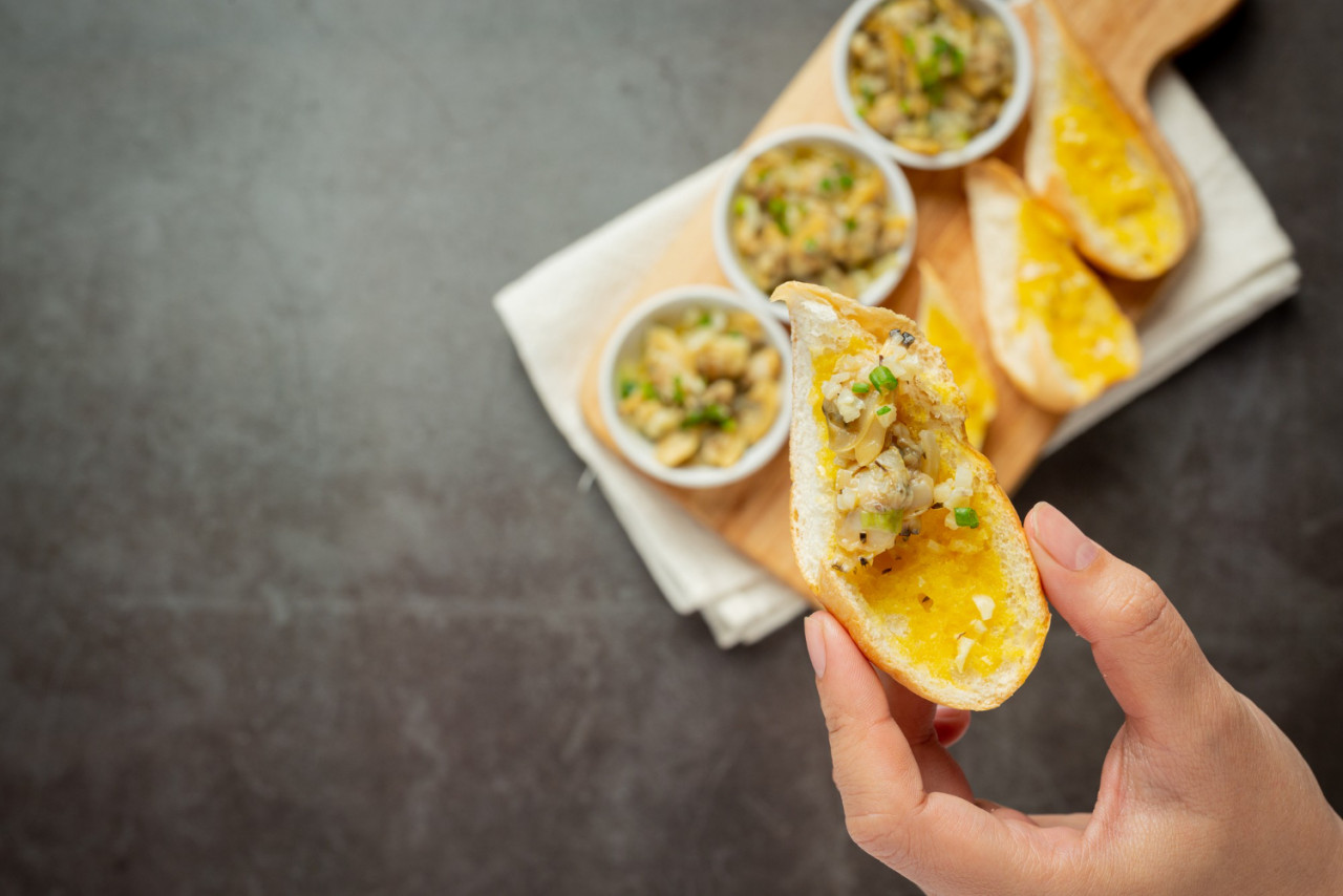 baked clam with garlic butter served with garlic bread dark background