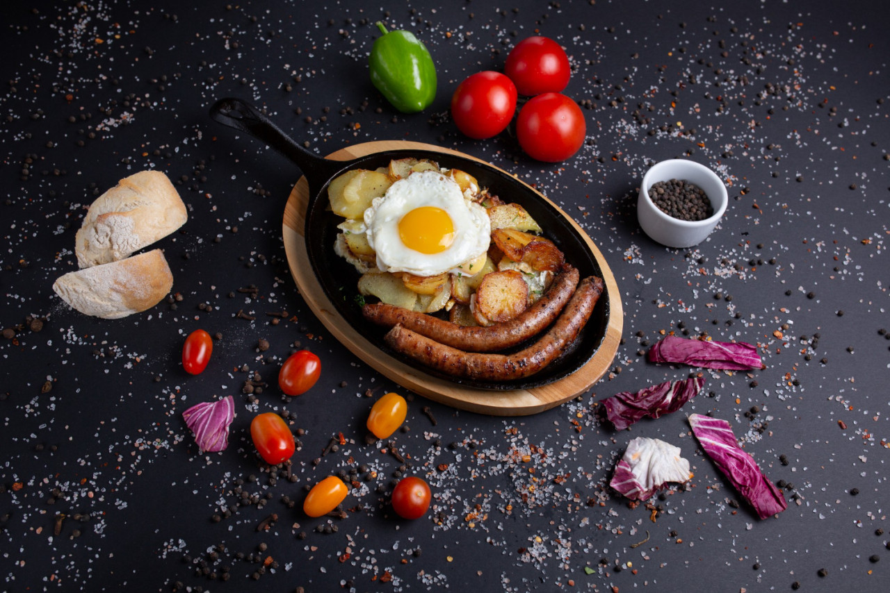 baked sausages with potatoes fried eggs black with red tomatoes bread red green peppers broccoli