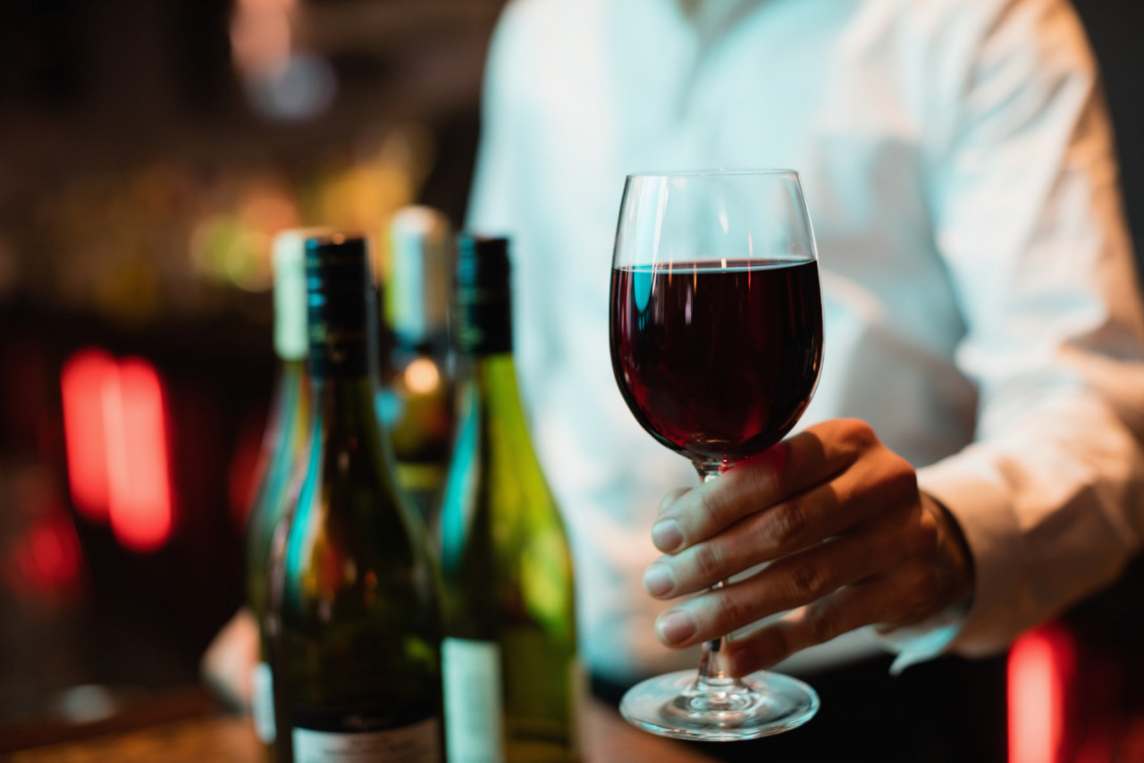 bartender holding glass red wine