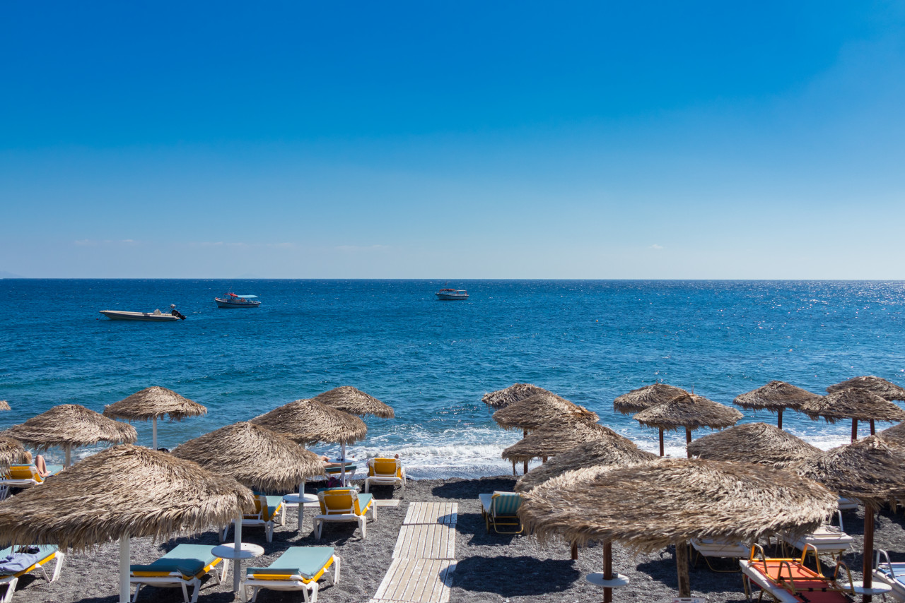 beach with umbrellas deck chairs by sea santorini
