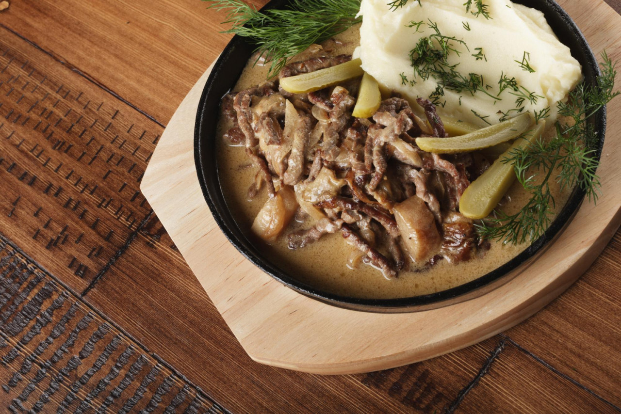 beef stroganoff with mushed potatoes pickled cucumbers pan wooden background