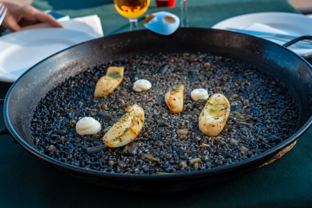 black rice with cuttlefish young garlic dry rice dish cooked paella clay pot characteristic flavor valencian mediterranean cuisine spain