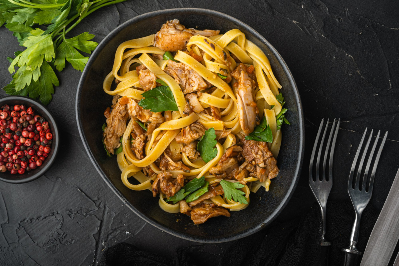 braised rabbit with rosemary garlic pasta tagliatelle pappardelle set bowl black stone background top view flat lay