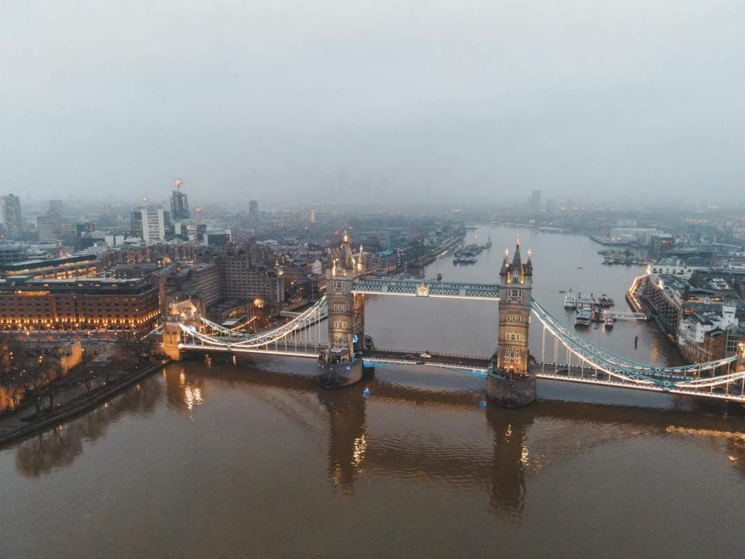 bridge over river near buildings in city in foggy day