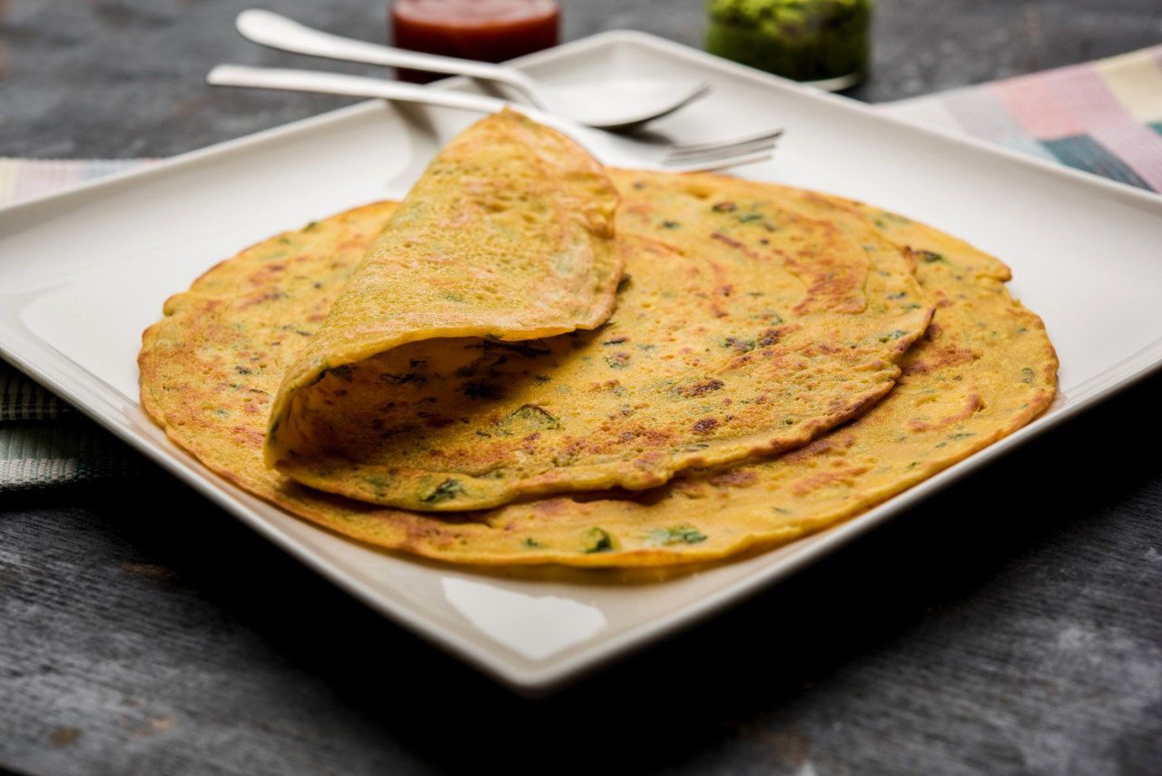 chilla besan cheela is simple pancake made with chickpea flour some basic ingredients served with green chutney tomato sauce also known as veg omelette
