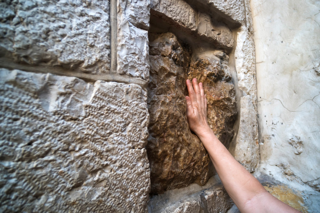 close up young man s hand touching old square stone with cavity which is said be imprint jesus hand handprint jesus station five via dolorosa jerusalem israel wall