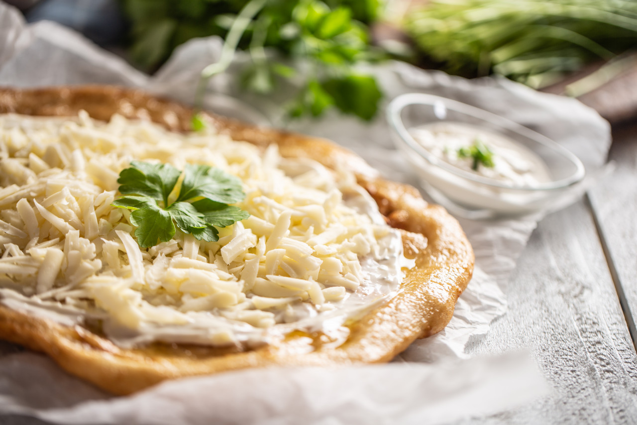 closeup hungarian baked langos served with loevly cream cheese garlic fresh green onion