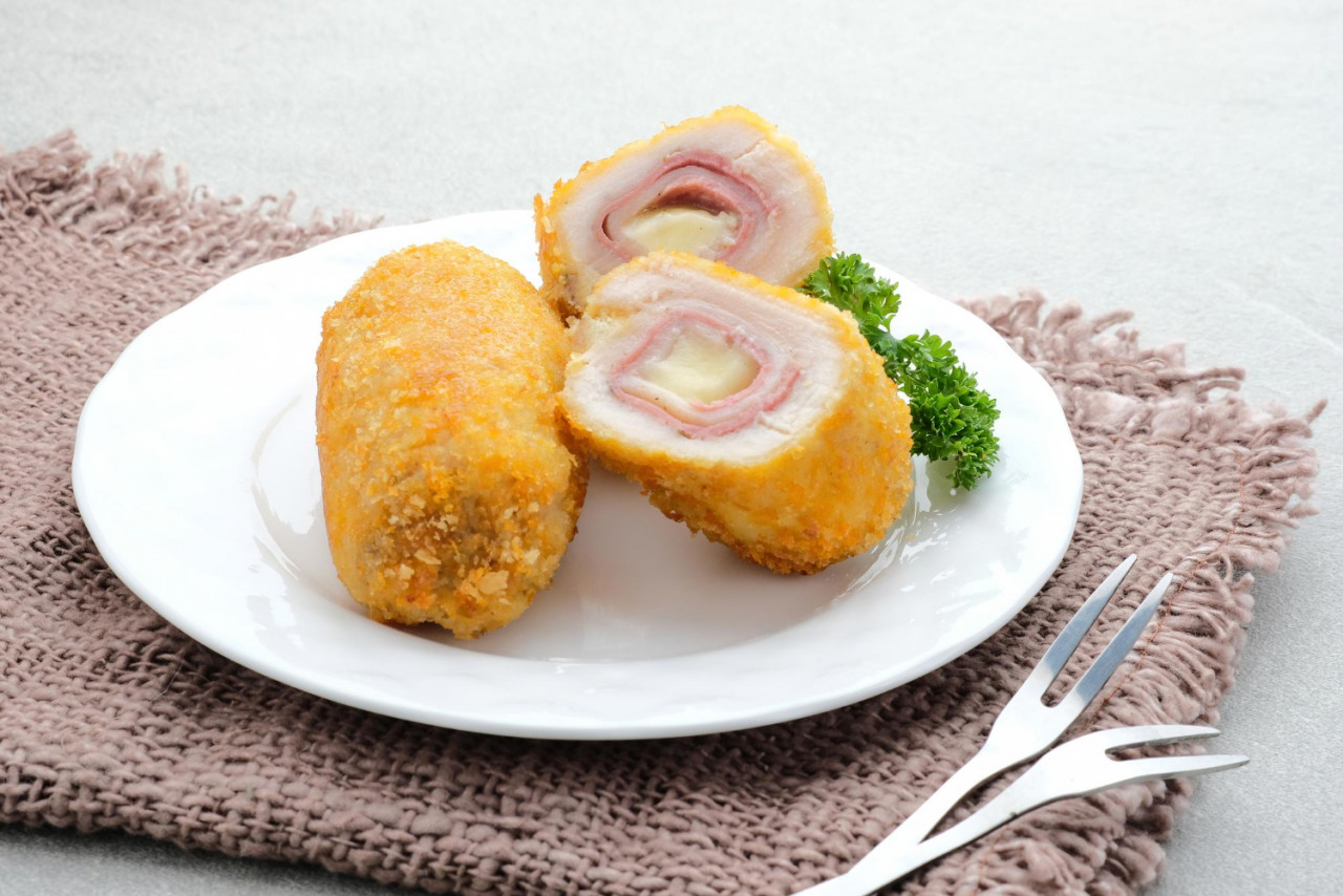 crispy cordon blue chicken fillet roll with ham and cheese served in plate on grey background