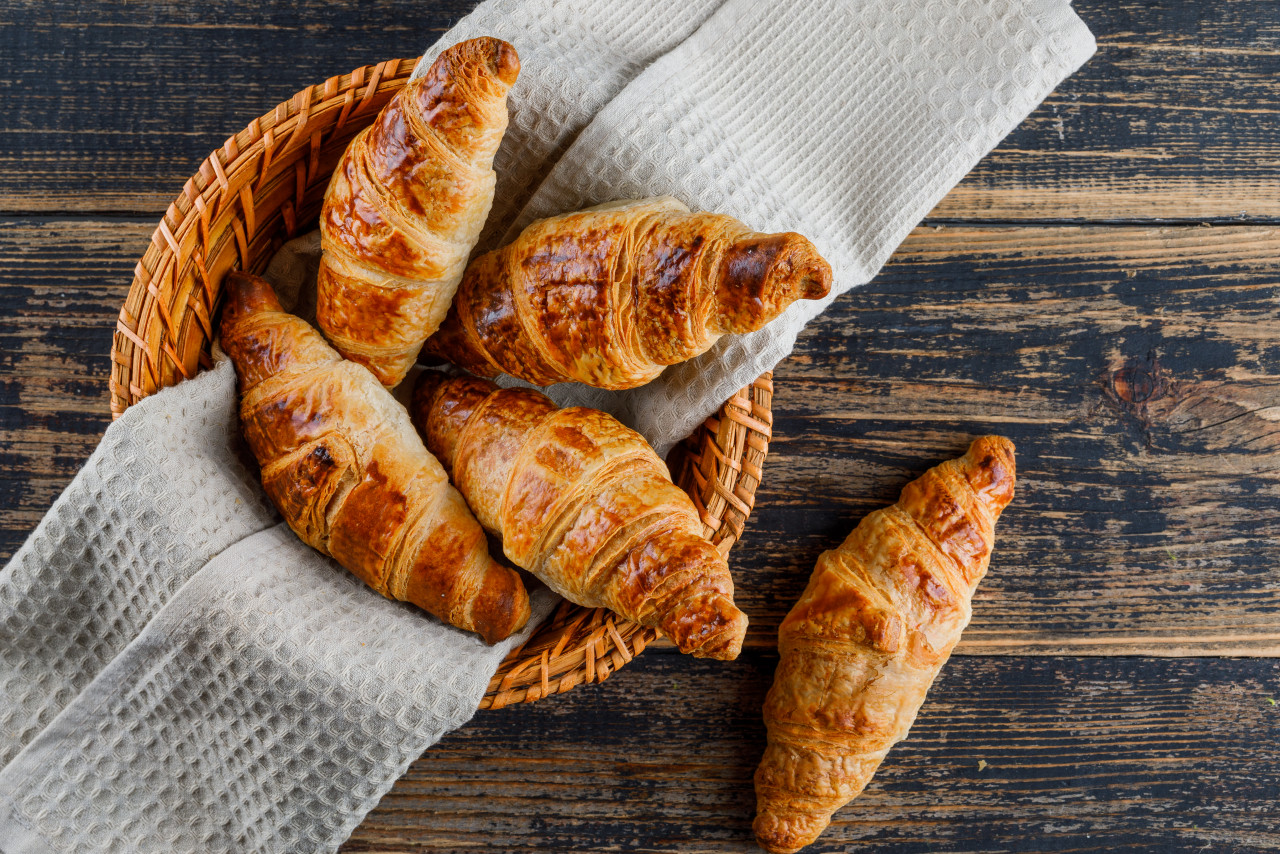 croissant basket with cloth wooden table flat lay