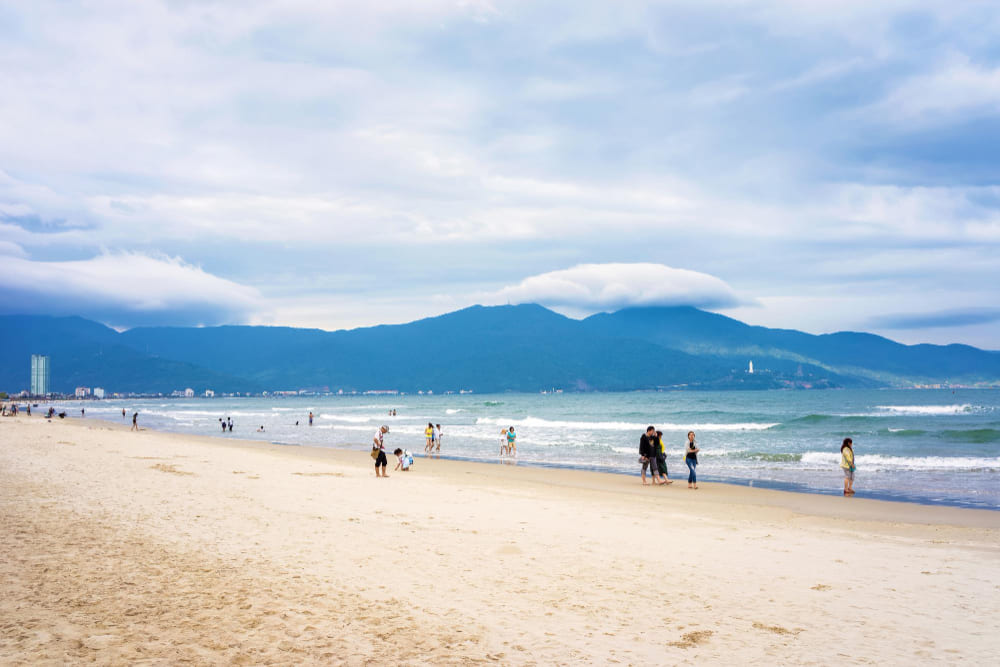 danang vietnam 20 febbraio 2016 turisti che camminano lungo la china beach a danang in vietnam si chiama anche spiaggia di non nuoc sullo sfondo il mar cinese meridionale e le montagne di marmo