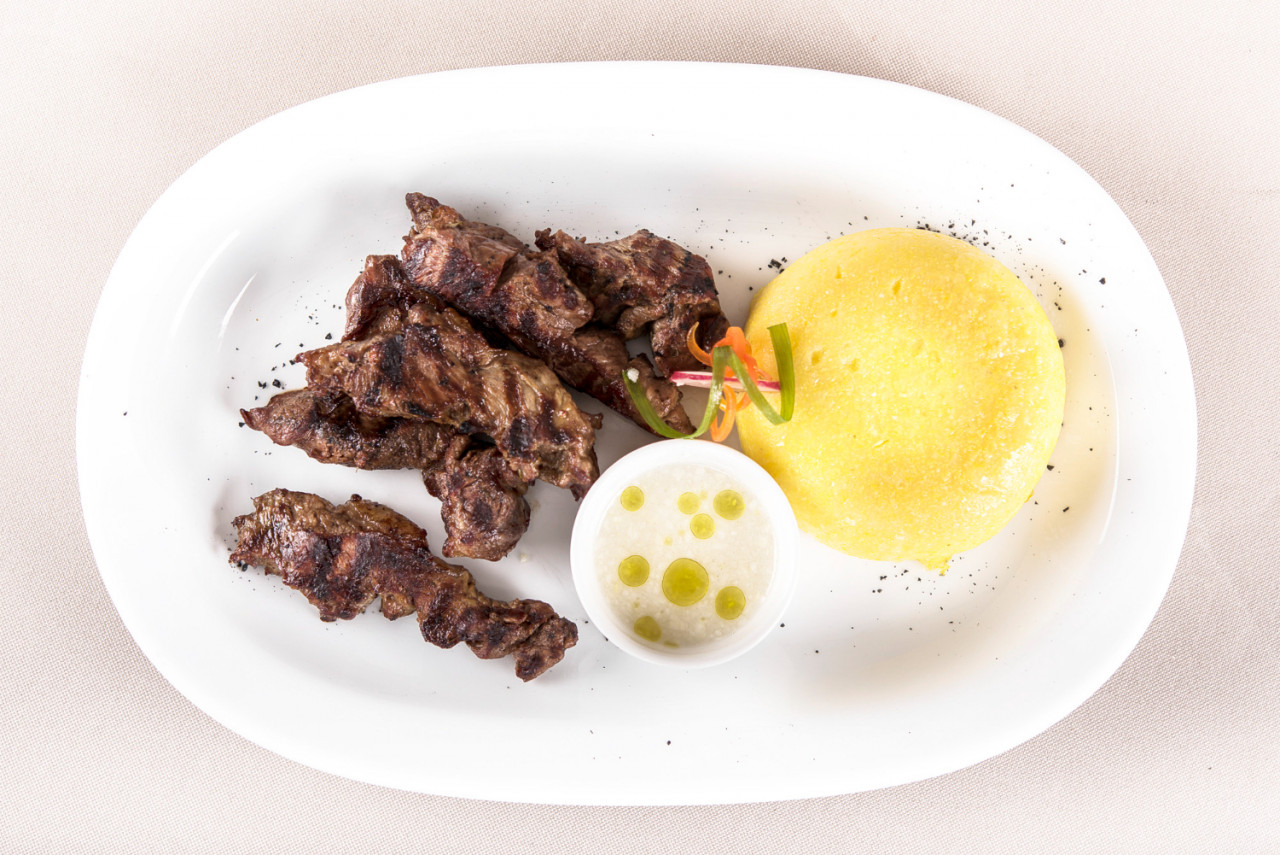 delicious grilled pork with polenta garlic sauce decorated with red green leaf