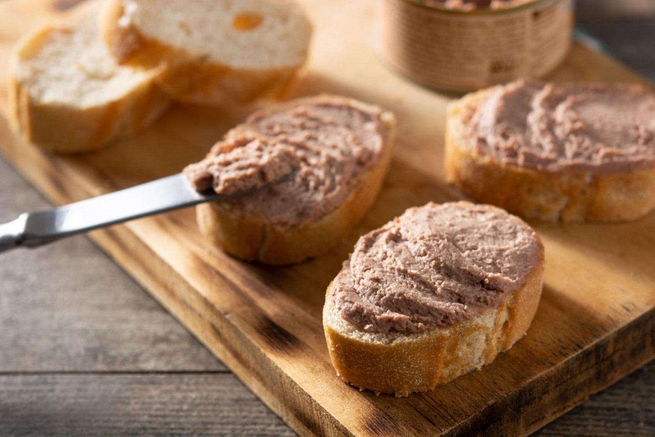 dipping toasted bread with pork liver pate wooden table