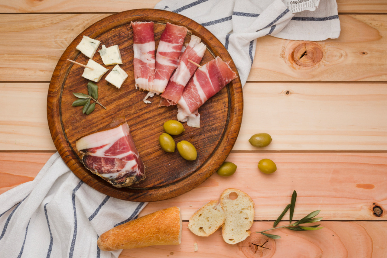 elevated view bacon olives cheese bread slices wooden circular board table