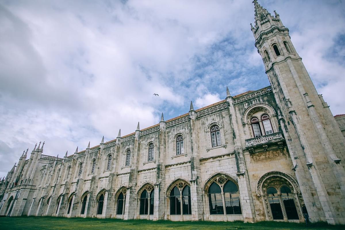 facade of jeronimos monastery near lawn under cloudy sky