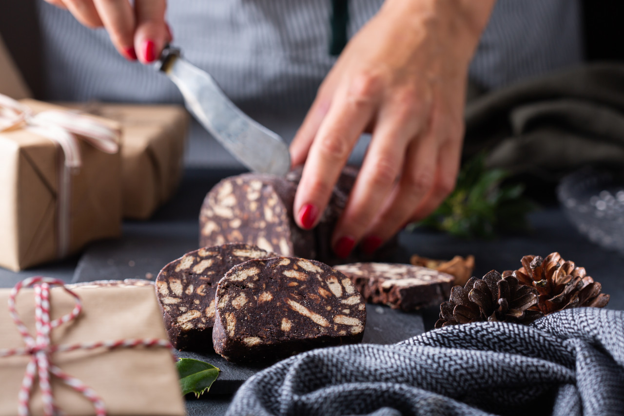 female hands cutting traditional italian dessert christmas chocolate salami