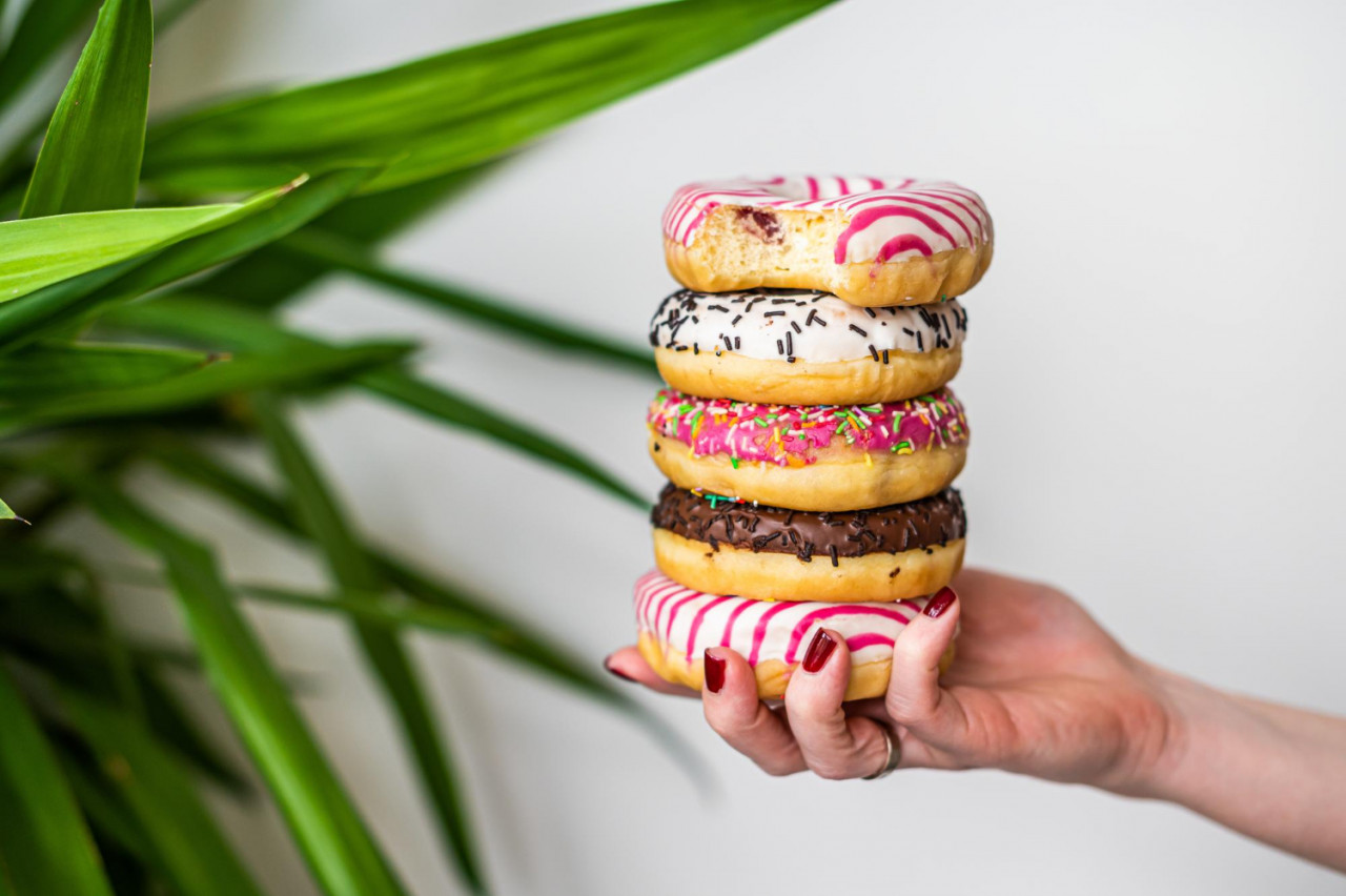 female holds hand colorful stack glazed donuts white background top view copy space