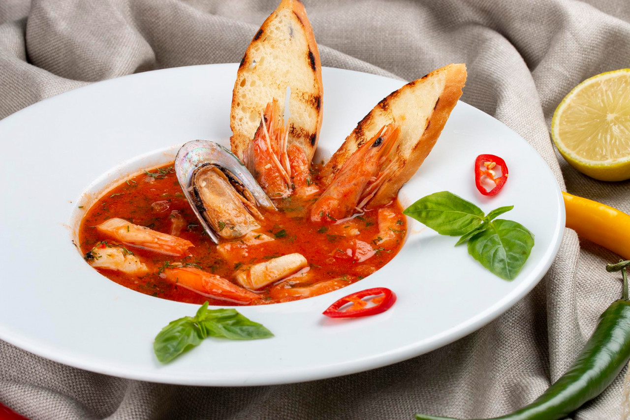 french bouillabaisse fish soup with shrimp mussels scallop white plate textile background