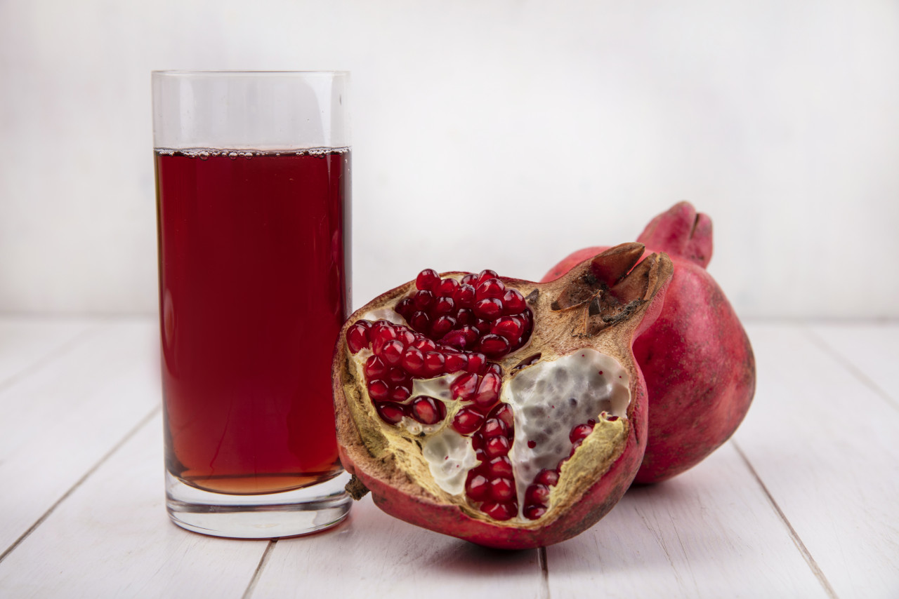 front view glass pomegranate juice with pomegranates white wall