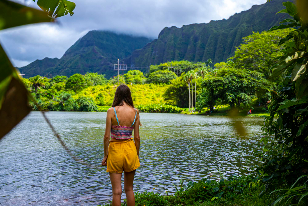 girl stands by lake full red fish ho omaluhia botanical garden admiring mighty mountains
