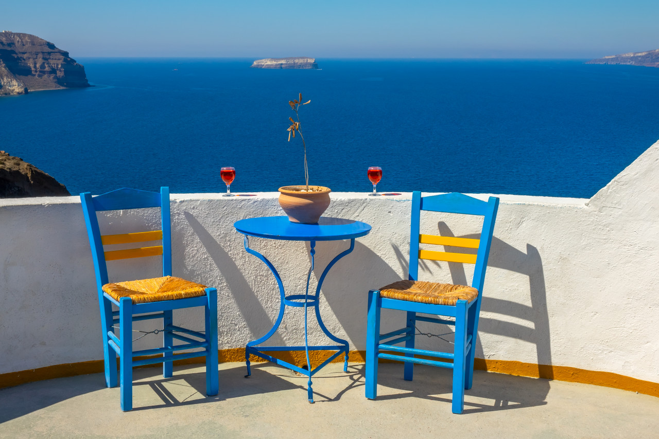 greece santorini thira island sunny seascape from cafe oia two glasses wine two chairs
