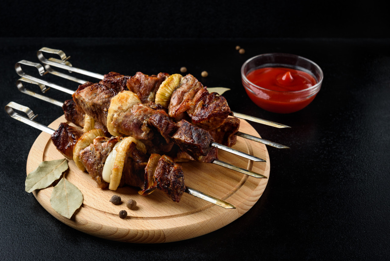 grilled meat skewers shish kebab with ketchup spices black background