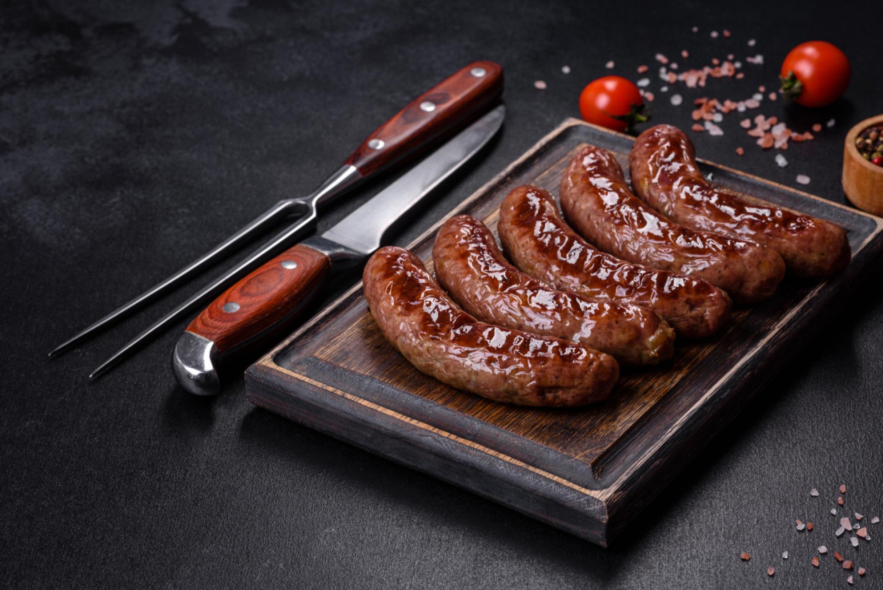 grilled sausages with ingredients cutting board stone background