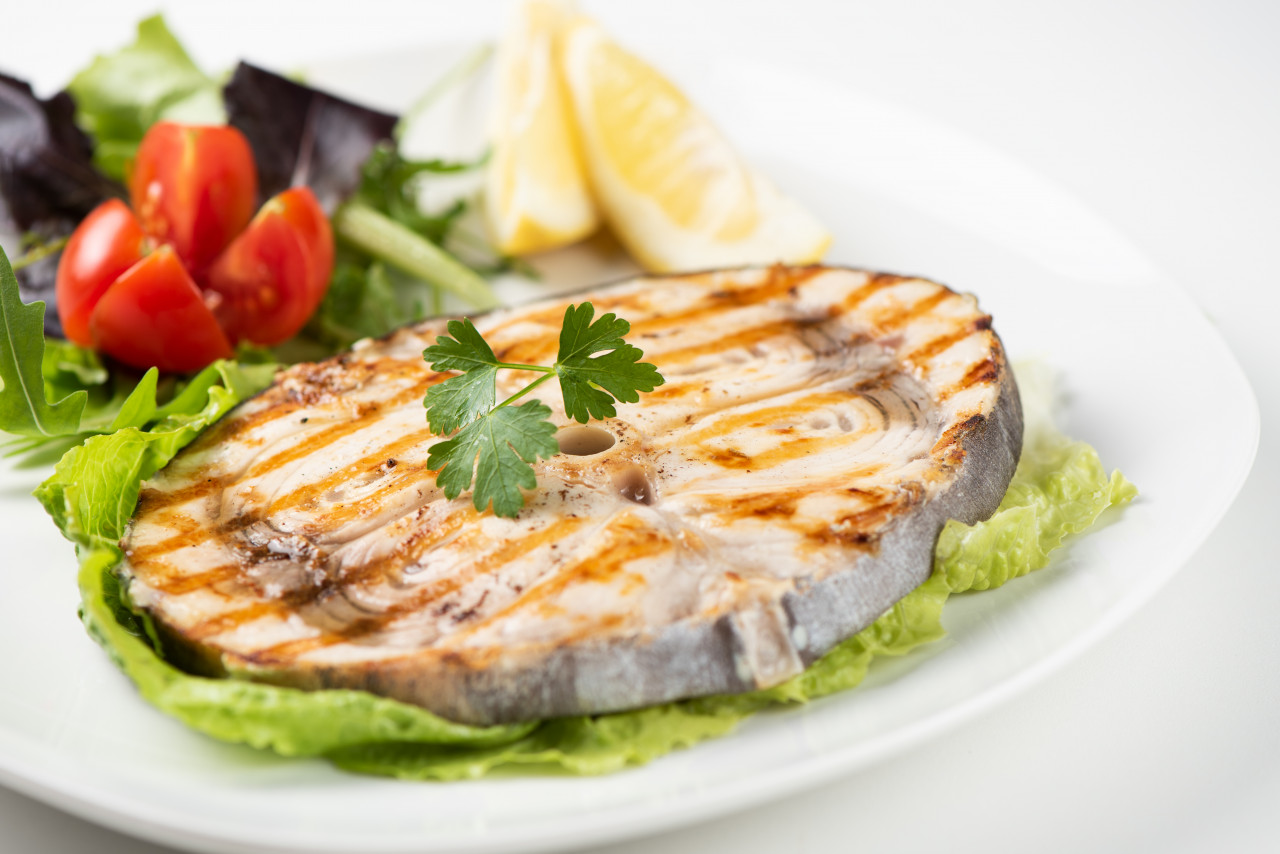 grilled swordfish with salad lemon white plate close up