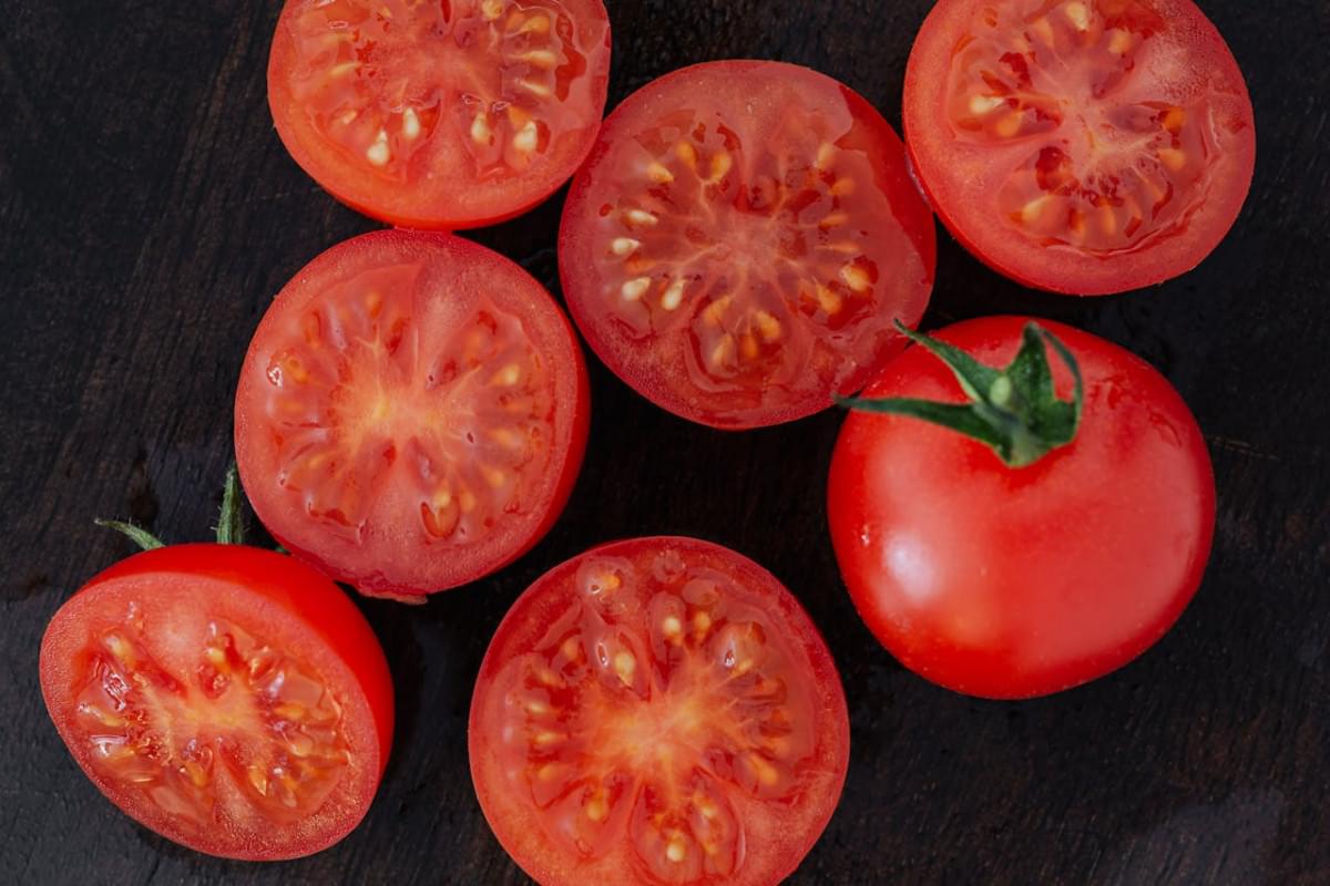 halves of tomatoes and whole tomato on cutting board