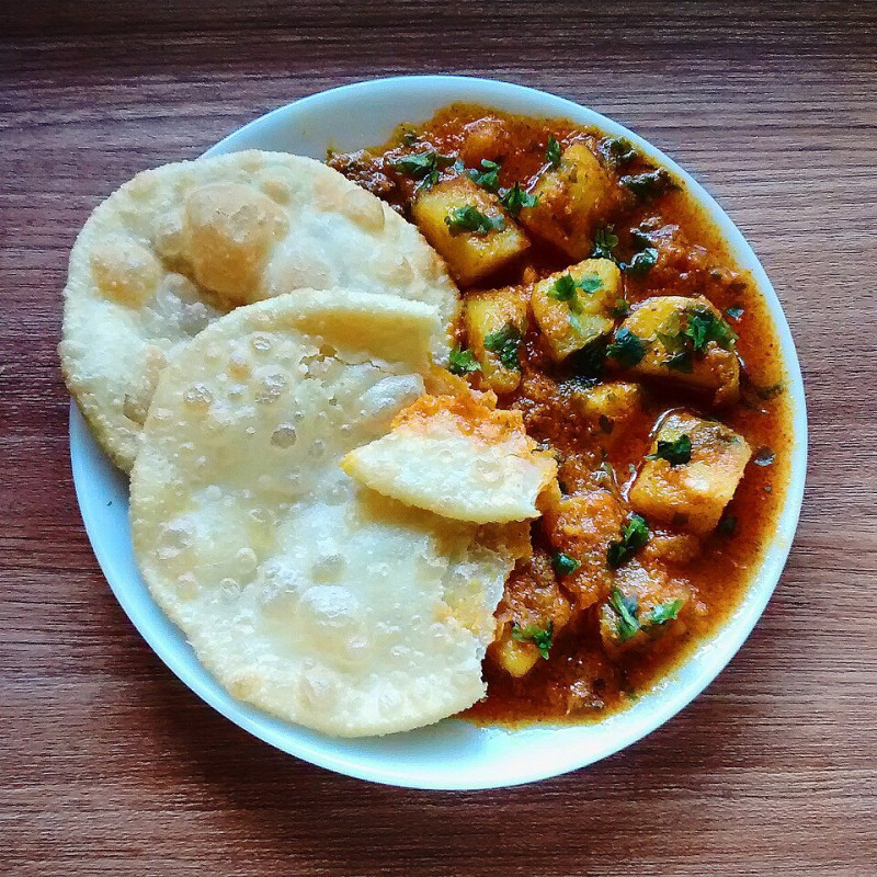 khatte mithe aloo sweet sour potato curry with maida poori deep fried puffy bread