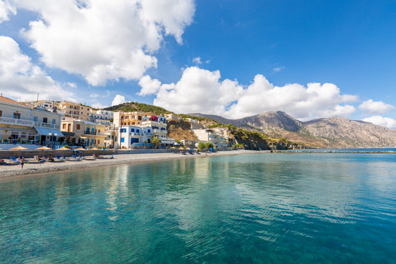 landscape sea surrounded by mountains buildings beaches blue cloudy sky greece