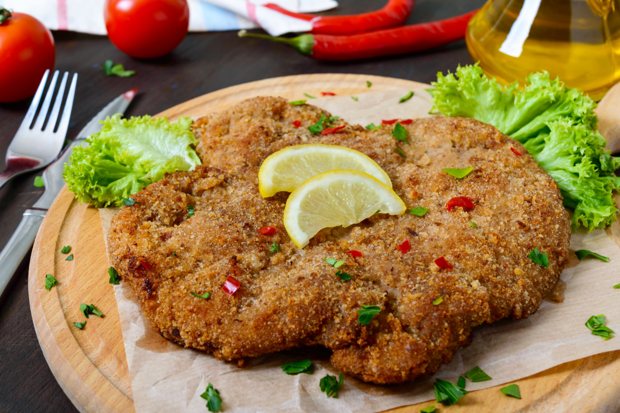 large viennese schnitzel wooden board with lemon dark background meat dish