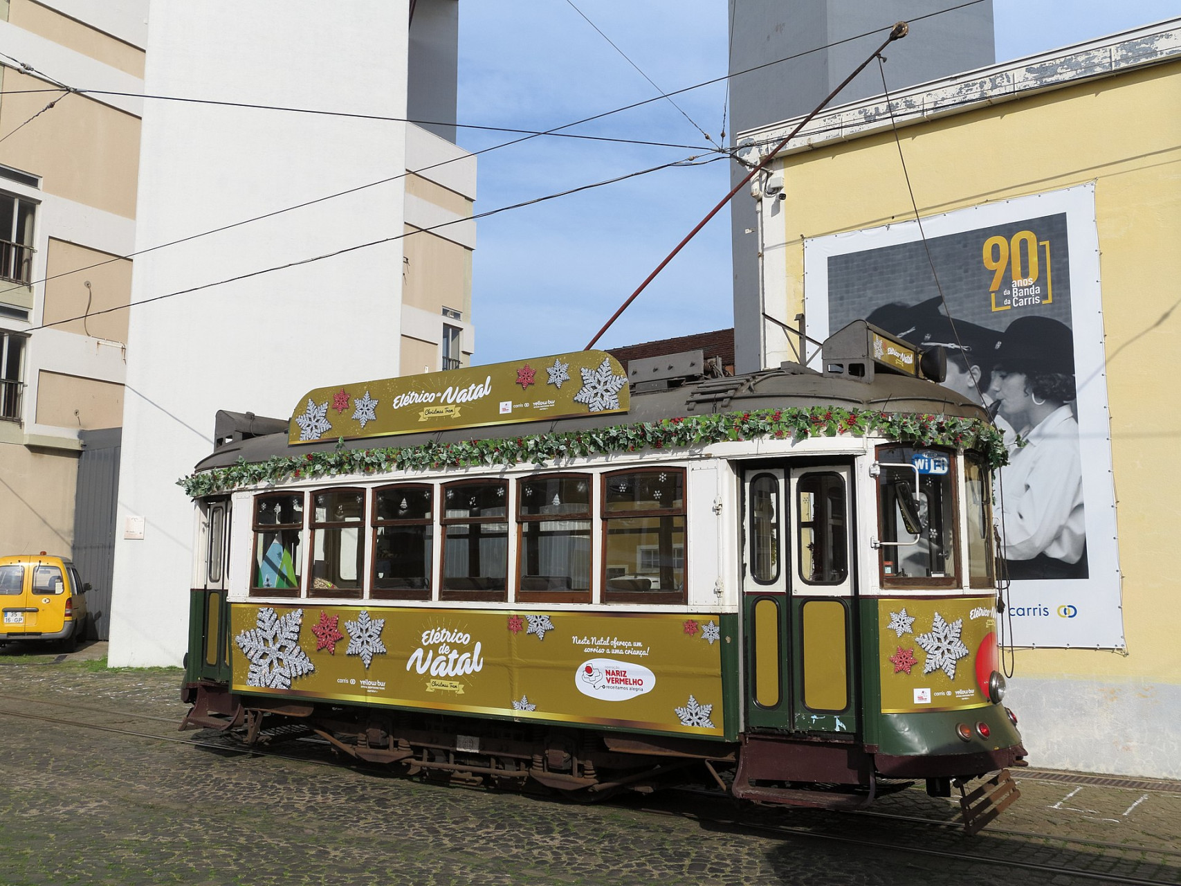 weihnachtsmann im begriff gelbe strassenbahn neben gebauden zu betreten