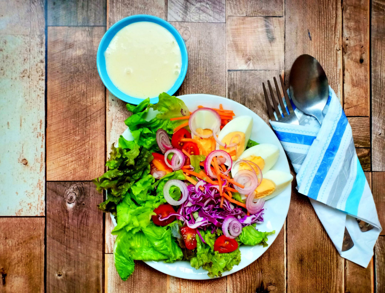 mixed green salad with hardboiled egg wooden background