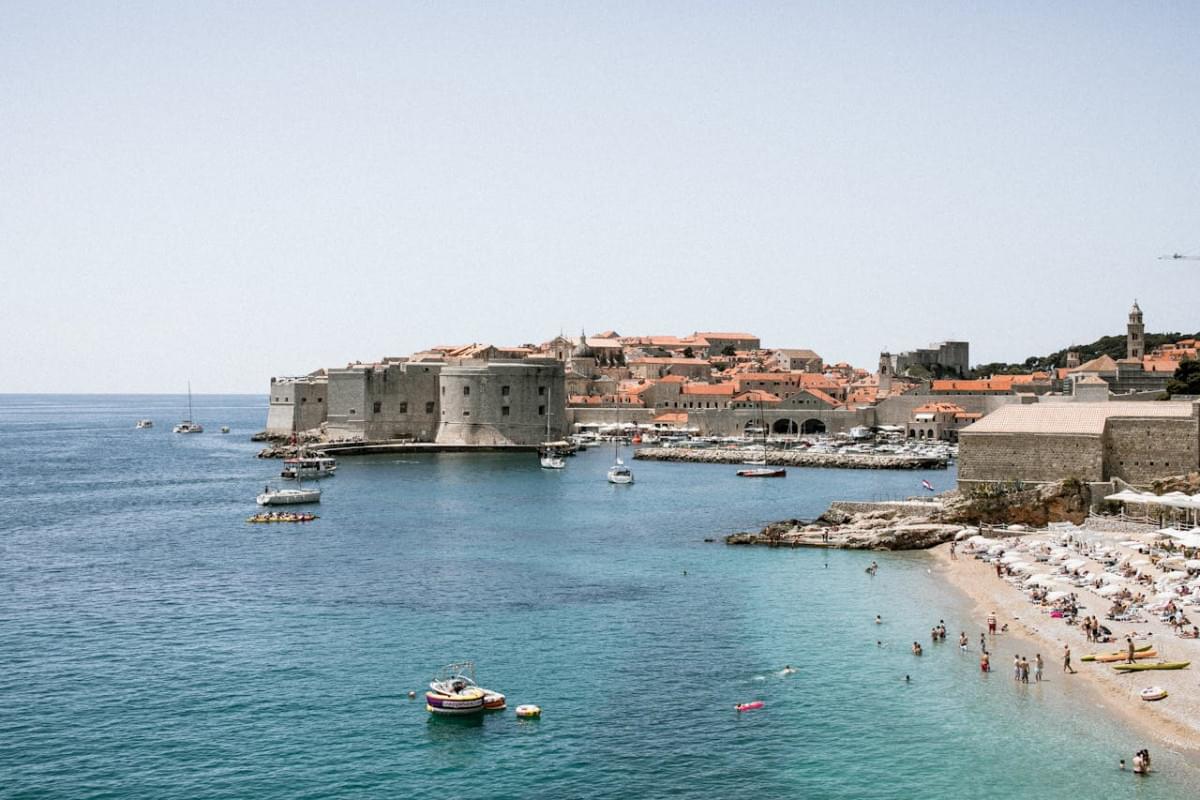 old stone fortress on shore with unrecognizable travelers against sea 1