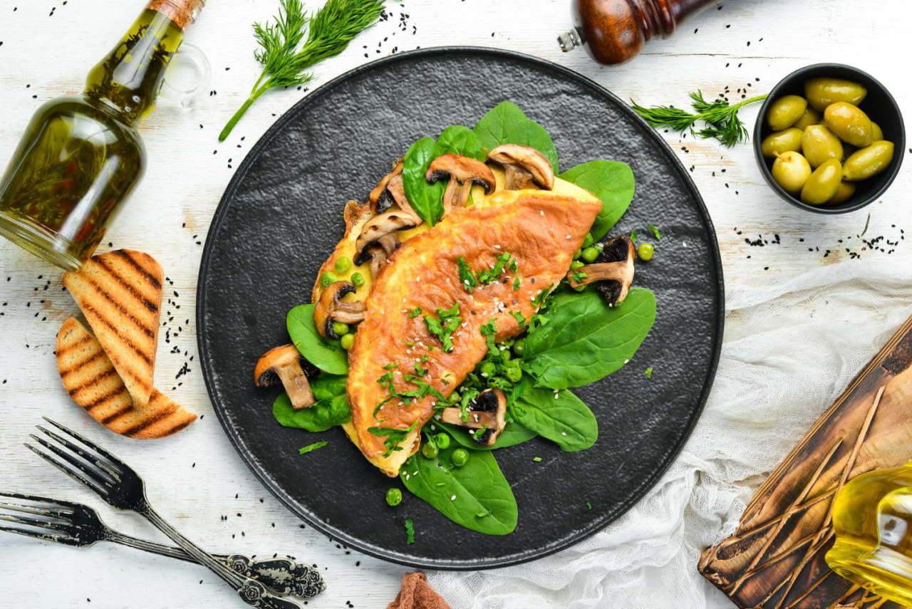 omelet with mushrooms and spinach in a black plate top view free space for your text 1